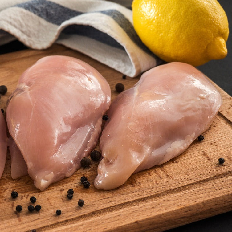 Buy Chicken Breast Fillets online. Fresh chicken breasts on wooden board with spices, olive oil and lemon